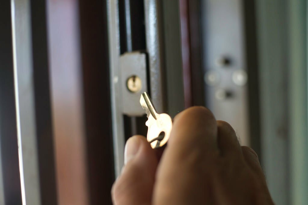 A close-up of a man holding a key to open a security gate