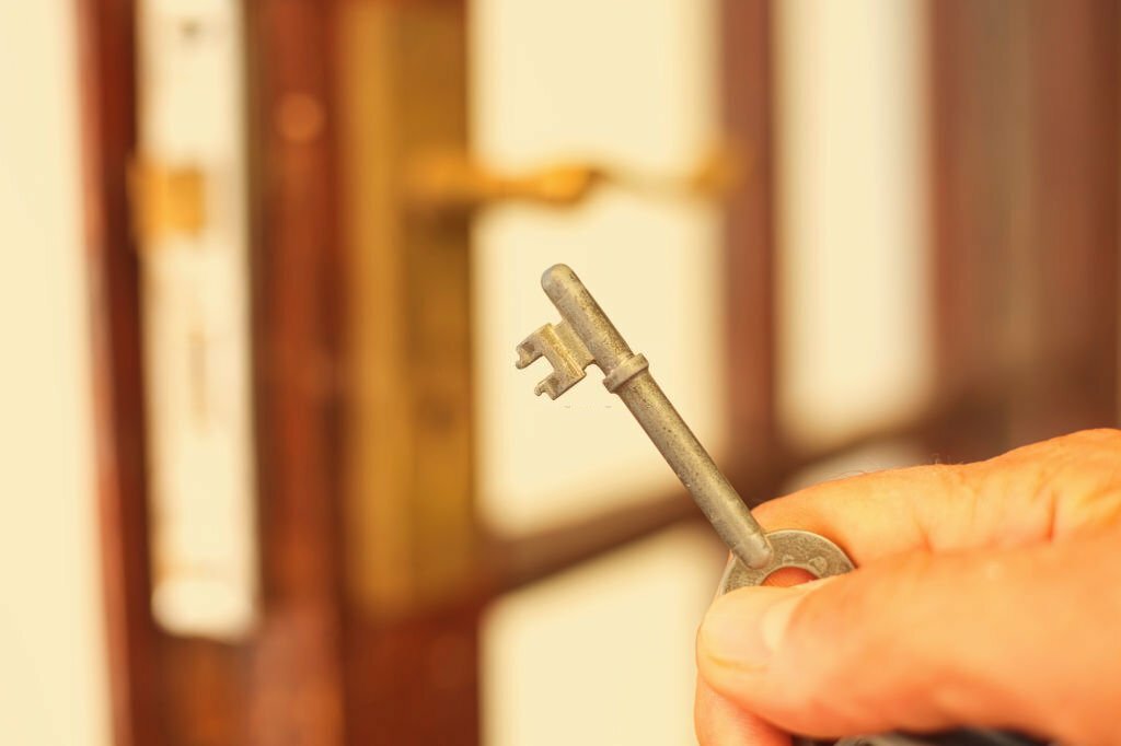 A close-up of a man holding a key to unlock  a door