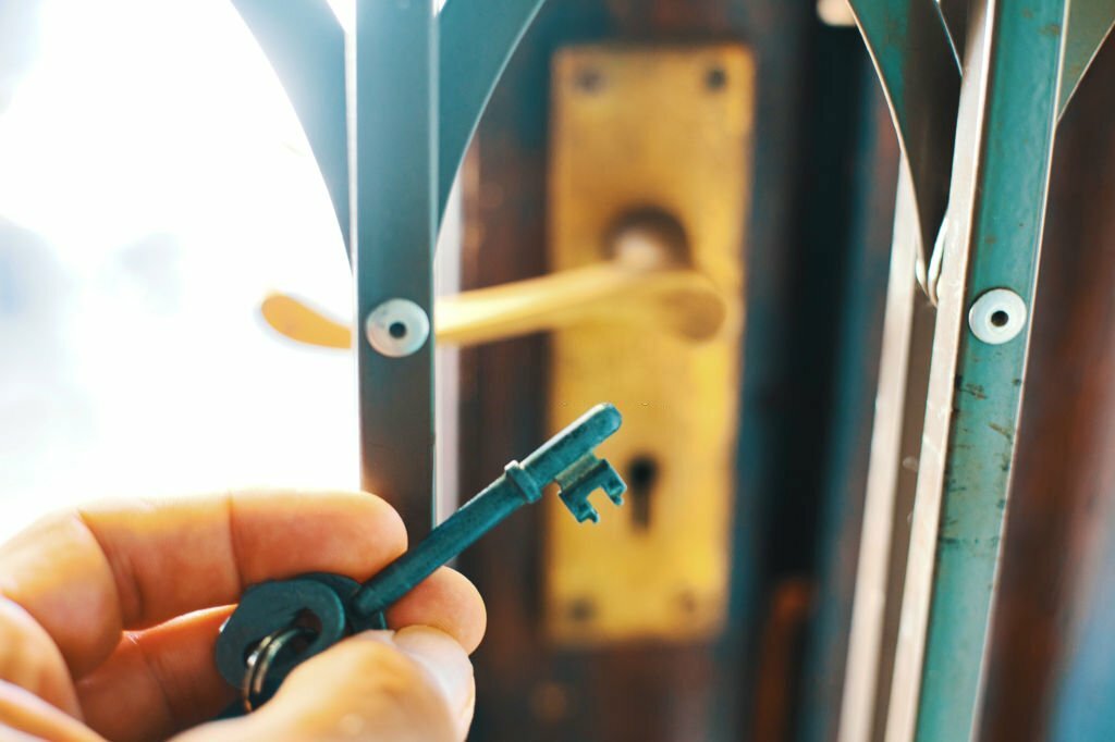 A close-up of a man holding a key to open a door behind a security gate