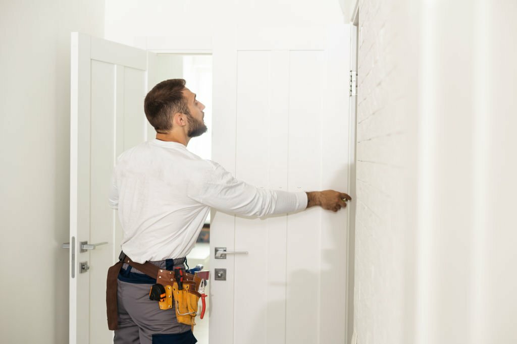 High Angle View Of Male Carpenter With Screwdriver Fixing Door Lock.