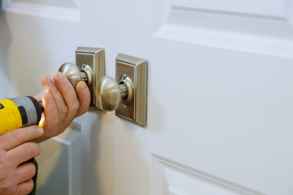 Master with screwdriver installs access the room door new dummy lock in house.