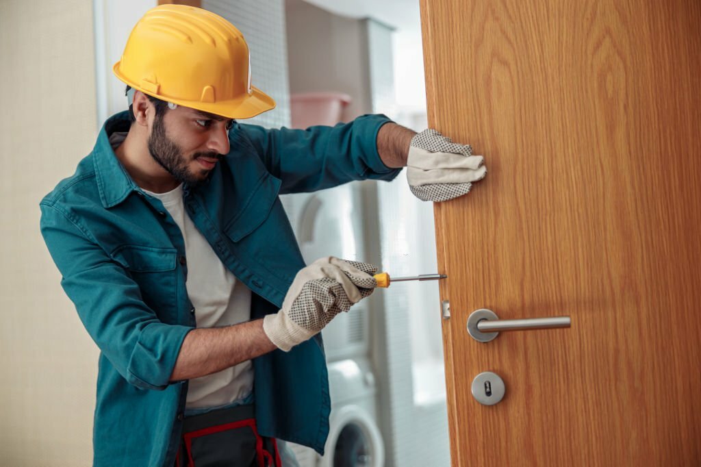 Locksmith workman in uniform installing door knob. Professional repair service. Maintenance Concept