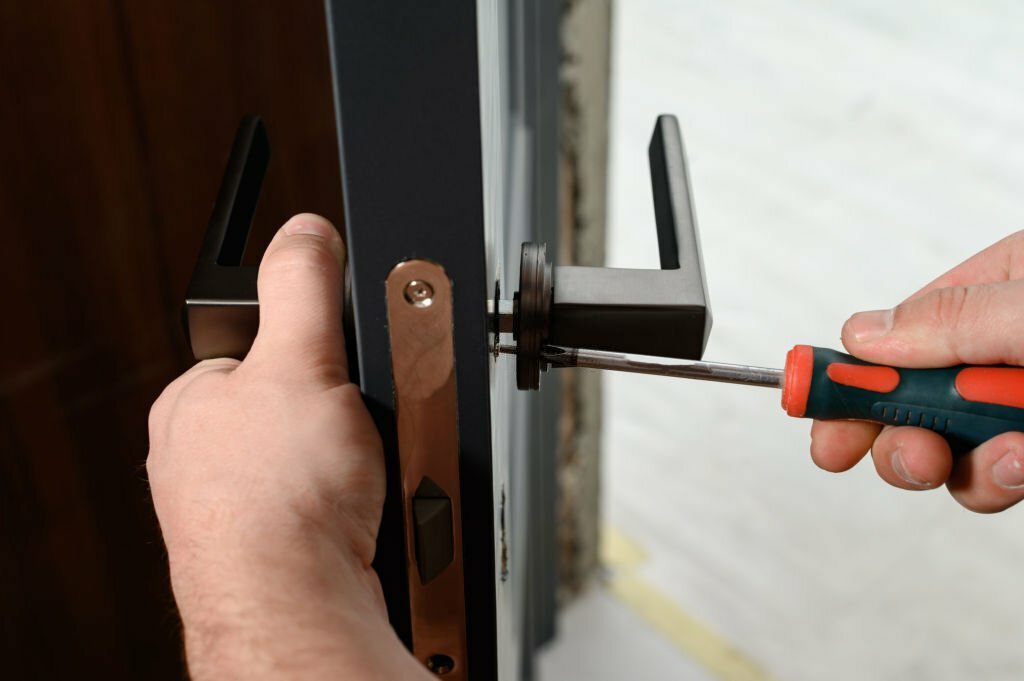 A man installs a door handle in a door, carpentry work at home, repair and restoration work.