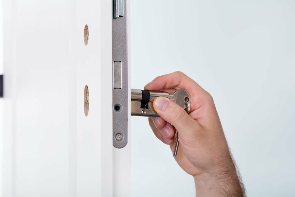 Close-up Of Man's Hand Installing Door Lock At Home