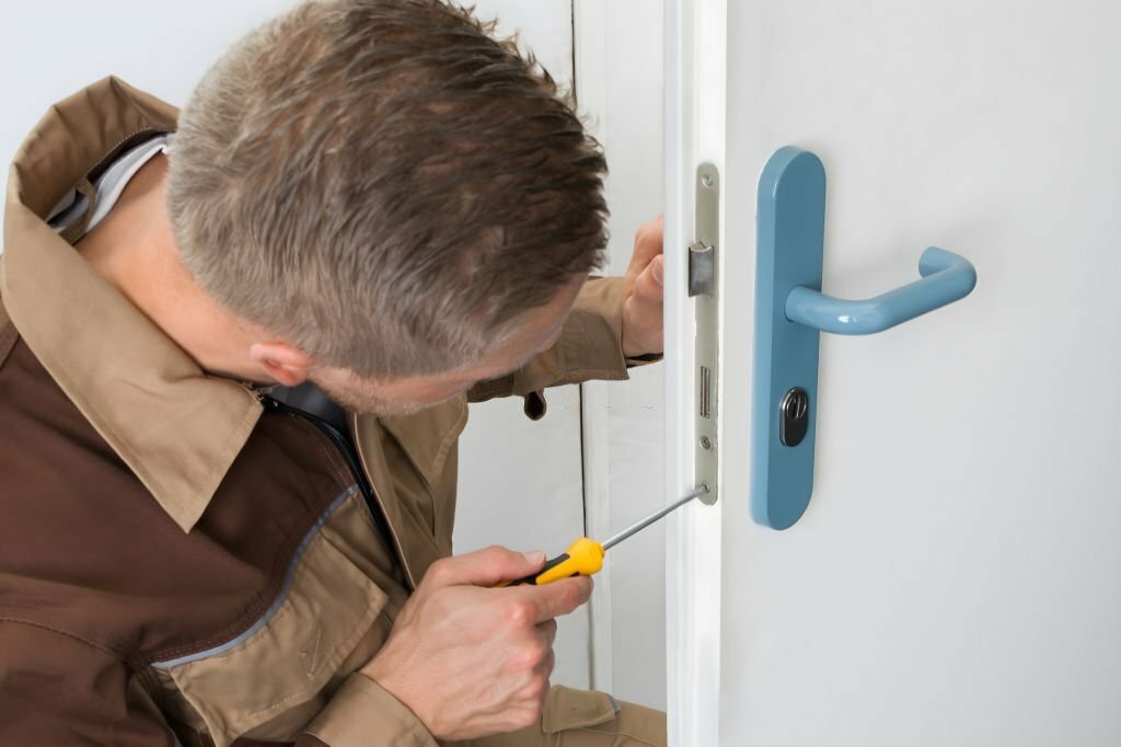 High Angle View Of Male Carpenter With Screwdriver Fixing Door Lock