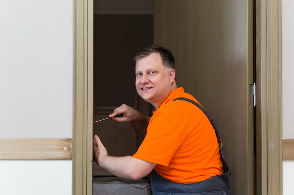 A man is installing a lock on the interior door of an apartment.