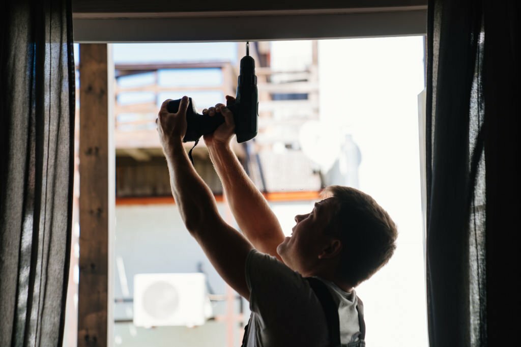 A silhouette of repairman repairs or adjusts window frames or glass doors on the terrace. services of a repairman or installer of furniture and doors.