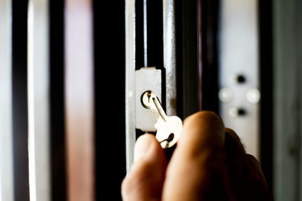 A close-up of a man holding a key to open a security gate