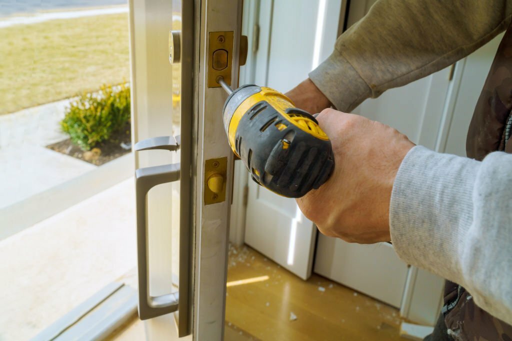 Worker installing lock in new house with using screwdriver