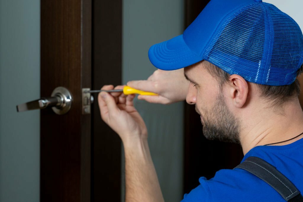 Handyman repair the door lock in the room. Closeup of man repairing the doorknob